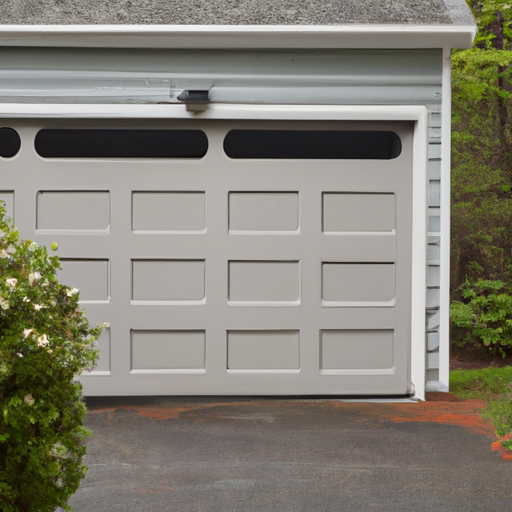 Suburban driveway in Sudbury with a closed steel paneled garage door and trimmed lawn, overcast light.